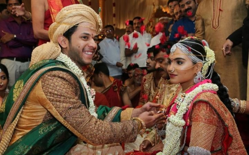 The daughter of Gali Janardhan Reddy, Bramhani (R) sits with her groom, Rajeev Reddy, during their wedding.